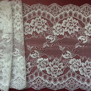 May include: White lace trim with a floral pattern. The lace has a scalloped edge and is approximately 1 inch wide.