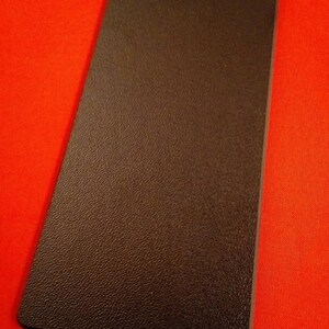 May include: A dark brown rectangular mat with a textured surface.