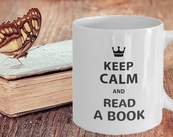 May include: White ceramic mug with a black crown and the text "Keep Calm and Read a Book". A butterfly is perched on a closed book.