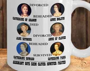 May include: White ceramic mug featuring portraits of the six wives of Henry VIII, with text indicating their fates: divorced, beheaded, died, divorced, beheaded, and survived. The mug is filled with pens and markers.