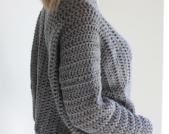 May include: A gray crocheted sweater with a loose fit and long sleeves. The sweater has a delicate openwork pattern.