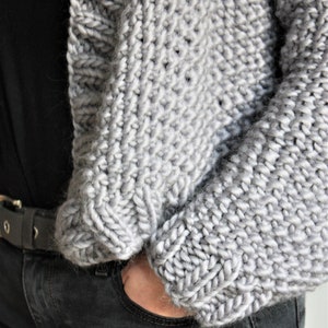 May include: A gray knitted cardigan with a loose fit and a textured stitch pattern.