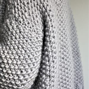 May include: A gray knitted sweater with a textured stitch pattern.