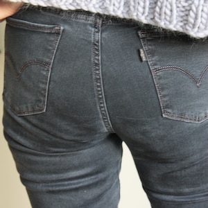 May include: A pair of dark gray denim jeans with a back pocket featuring a small, white logo.