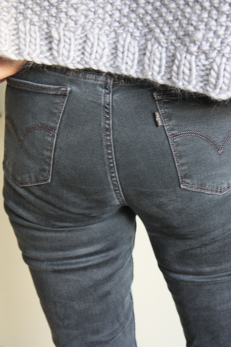 May include: A pair of dark gray denim jeans with a back pocket featuring a small, white logo.