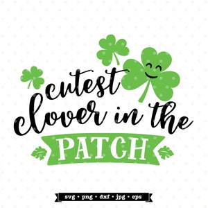 May include: A green shamrock with a smiling face and the text "cutest clover in the patch" in black cursive font. The text is on a green banner with white letters. The image also includes two smaller shamrocks.