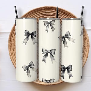 May include: Three stainless steel tumblers with a white background and a black and white bow pattern.