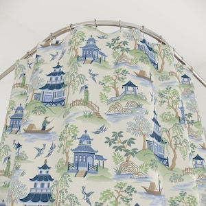 Puede incluir: Cortina de ducha con un diseño paisajístico de inspiración asiática. Presenta pagodas azules, árboles, figuras y barcos sobre un fondo crema. El patrón se repite, creando un aspecto decorativo y armonioso.