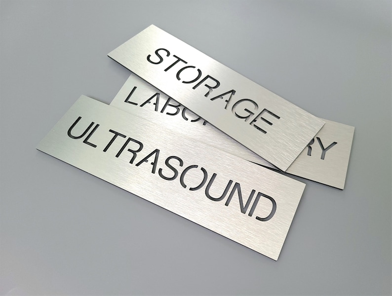 May include: Three silver metal signs with black lettering. The signs read "Storage", "Laboratory", and "Ultrasound".