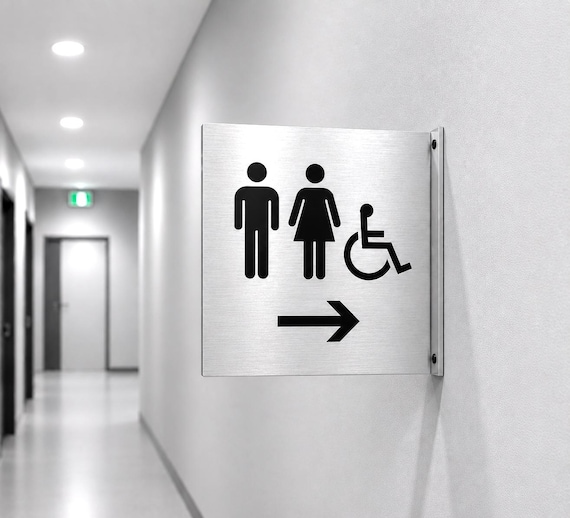 Double-sided directional restroom sign for perpendicular mounting. Corridor wayfinding signage. Blade signs. Flag signs. Sign with arrow.