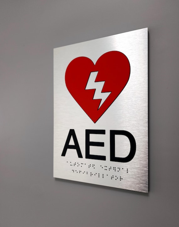 ADA AED sign. Fire emergency ADA compliant signs. Automated external defibrillator sign with red pictogram and Grade 2 Braille.