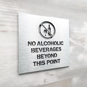 May include: A silver metal sign with a no alcohol symbol and the text "NO ALCOHOLIC BEVERAGES BEYOND THIS POINT".