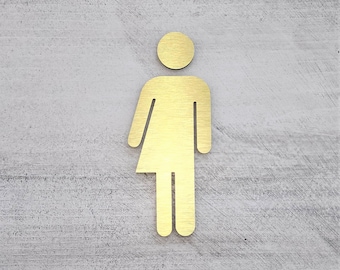May include: A gold-colored gender-neutral restroom sign on a gray textured wall.