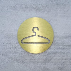 May include: A gold-colored round sign with a hanger silhouette in the center.