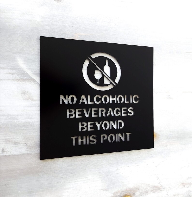 May include: Black metal sign with a white silhouette of a crossed out wine glass and bottle. The sign reads "NO ALCOHOLIC BEVERAGES BEYOND THIS POINT."