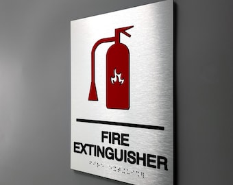 May include: A silver metal sign with a red fire extinguisher icon and the text "FIRE EXTINGUISHER" in black. The sign also includes braille text.