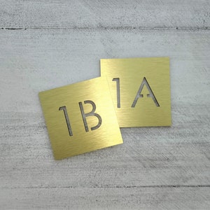 May include: Two gold metal plaques with the numbers "1A" and "1B" engraved on them.