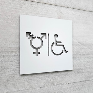 Pode incluir: Placa branca com símbolos recortados para banheiros neutros em gênero e acessíveis. Os símbolos incluem um símbolo transgênero, um símbolo de cadeira de rodas e uma pessoa em cadeira de rodas.