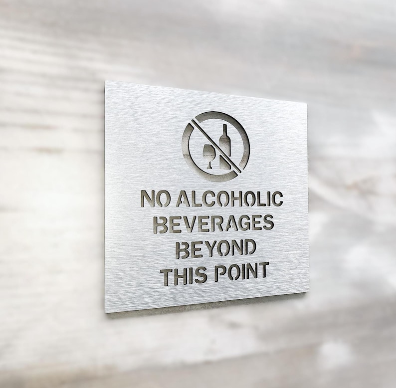 May include: A silver metal sign with a no alcohol symbol and the text "NO ALCOHOLIC BEVERAGES BEYOND THIS POINT".