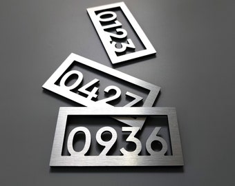 May include: Three silver metal house number plaques with the numbers 0427, 0936, and 123. The plaques are stacked on top of each other.
