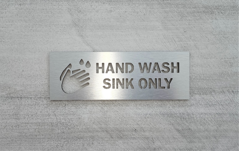 May include: A silver metal sign with the text "HAND WASH SINK ONLY" and a cut-out image of a hand washing with water droplets.