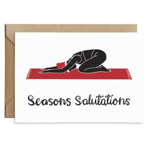 May include: A greeting card with a black silhouette of a person in a yoga pose on a red mat. The card reads "Seasons Salutations" in black script. The card is inside a brown envelope.
