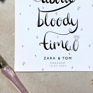 K&ouml;nnte beinhalten: Eine wei&szlig;e Karte mit schwarzer Kalligraphie, die "bloody time" mit einer Diamantring-Illustration zeigt. Die Namen "ZARA & TOM" und das Datum "10.07.2024" sind ebenfalls auf der Karte abgedruckt, zusammen mit kleinen Herzillustrationen.