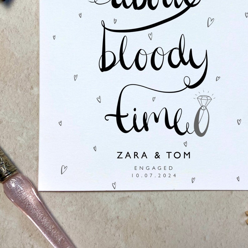 K&ouml;nnte beinhalten: Eine wei&szlig;e Karte mit schwarzer Kalligraphie, die "bloody time" mit einer Diamantring-Illustration zeigt. Die Namen "ZARA & TOM" und das Datum "10.07.2024" sind ebenfalls auf der Karte abgedruckt, zusammen mit kleinen Herzillustrationen.