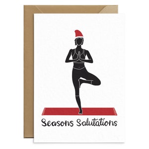 May include: A Christmas-themed greeting card featuring a black silhouette of a person in a yoga pose, wearing a Santa hat. The person is standing on a red yoga mat. The words "Seasons Salutations" are written in black script.