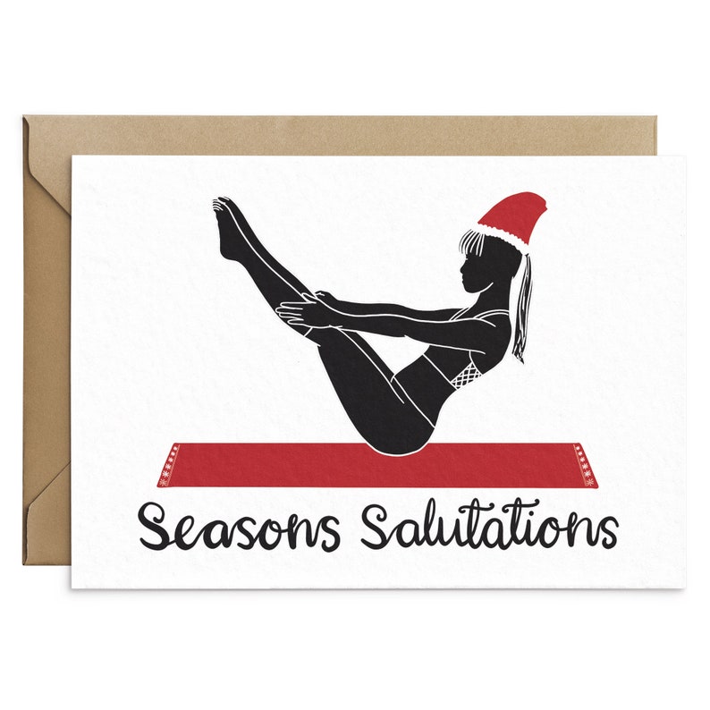 May include: A holiday greeting card featuring a black silhouette of a person in a yoga pose, wearing a Santa hat. The person is on a red yoga mat. The words "Seasons Salutations" are written in black script below the image. The card is inside a brown envelope.