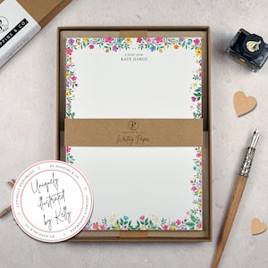 May include: A floral stationery set with white paper, a pen, and ink. The paper has a colourful border of flowers in pink, yellow, blue, and green. The text "a letter from KATE HARDY" is printed on the paper.