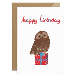 May include: A birthday card with a red and blue "happy birthday" greeting. A brown owl with yellow eyes sits on top of a red gift box with a blue ribbon and a "for you" tag.