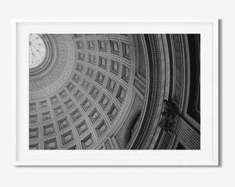 May include: Black and white framed print of a building's interior, showcasing a detailed dome ceiling with geometric patterns. The image captures architectural details, including a central oculus and a decorative column.