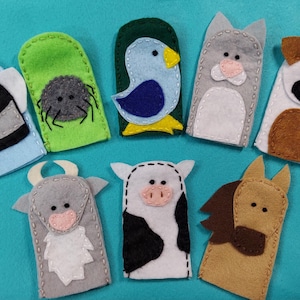 May include: A set of eight felt finger puppets featuring various animal and insect designs, including a bee, spider, bird, cat, dog, bull, cow, and horse, all crafted with stitched details and distinct color patterns on a solid teal background.