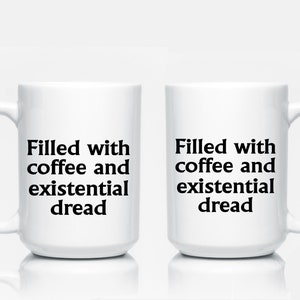May include: Two white ceramic mugs with black text that reads "Filled with coffee and existential dread".