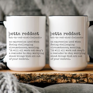 K&ouml;nnte beinhalten: Zwei wei&szlig;e Keramikbecher mit schwarzen Henkeln und schwarzen R&auml;ndern. Die Becher zeigen den isl&auml;ndischen Ausdruck "&thorn;etta reddast" (ausgesprochen "teh-ta-red-ahst") und seine Bedeutung: "ein Ausdruck, der verwendet wird, wenn man mit herausfordernden Umst&auml;nden konfrontiert ist, was bedeutet: "es wird alles gut gehen"; eine Erinnerung daran, aufzuh&ouml;ren, sich &uuml;ber Dinge zu sorgen, die au&szlig;erhalb unserer Kontrolle liegen."