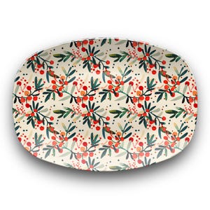 May include: An oval serving platter with a cream background. It features a repeating pattern of red berries, green leaves, and small black dots. The design has a festive, holiday feel, perfect for serving food.