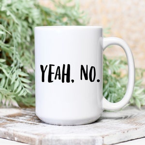 May include: White ceramic coffee mug with black text that reads "YEAH. NO."