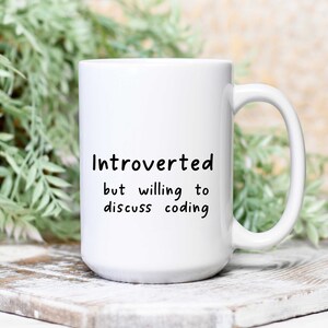 Peut inclure: Une tasse en céramique blanche avec du texte noir qui dit "Introverti mais prêt à discuter de la programmation".