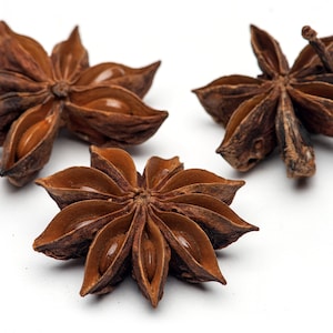 May include: Three brown star anise pods isolated on a white background.