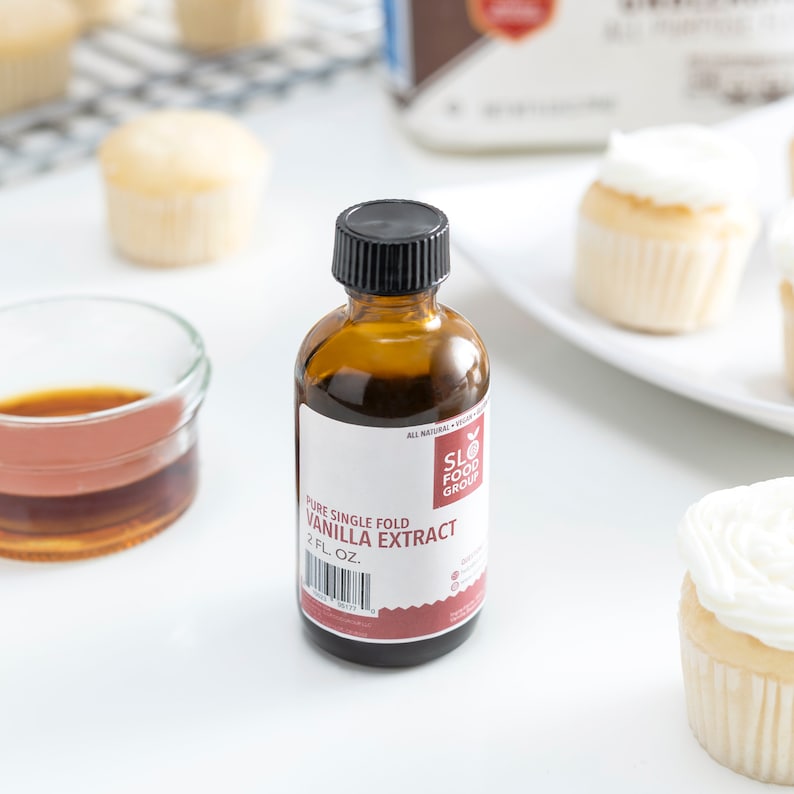 May include: A 2-ounce bottle of pure single fold vanilla extract. The bottle is brown glass with a black cap and a red and white label. The label says "SLO FOOD GROUP" and "PURE SINGLE FOLD VANILLA EXTRACT".