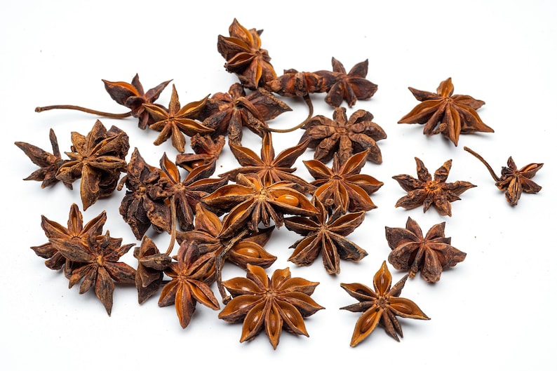 May include: A collection of dried star anise pods, a popular spice used in Asian cuisine, scattered on a white background.