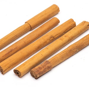 May include: Five brown cinnamon sticks on a white background.