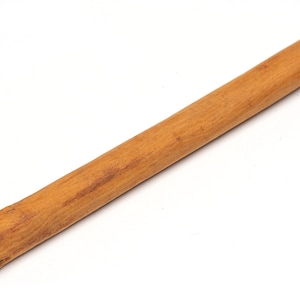 May include: A single cinnamon stick, brown in color, with a rough texture. The stick is lying on a white surface.
