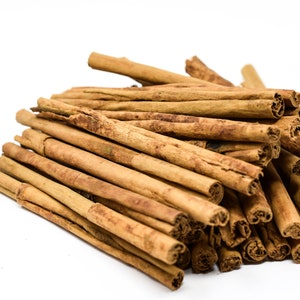 May include: A pile of brown cinnamon sticks on a white background.