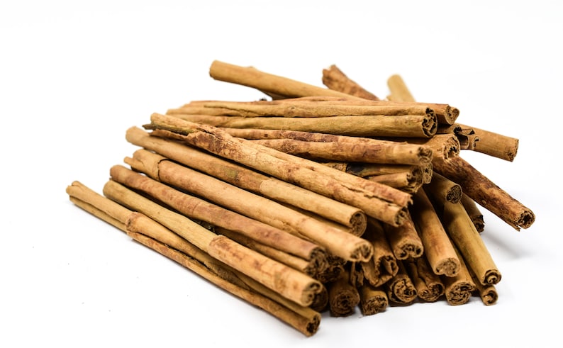 May include: A pile of brown cinnamon sticks on a white background.