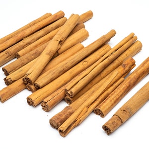 May include: A pile of brown cinnamon sticks on a white background.