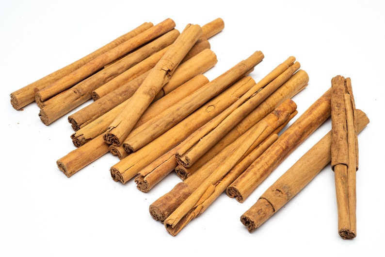 May include: A pile of brown cinnamon sticks on a white background.