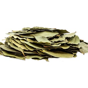 May include: A pile of dried bay leaves, a common culinary herb, arranged in a loose mound on a white background.