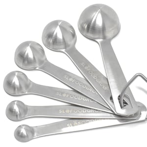 May include: A set of five stainless steel measuring spoons with a ring handle. The spoons are labeled "SLOFOODGROUP".